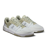 On THE ROGER Clubhouse men's tennis shoes in white with blue accents, featuring a sleek design and cushioned sole.