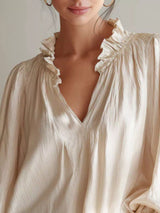 Black frill notched long sleeve blouse from Trendsi featuring a V-neck with ruffle details and a relaxed fit.