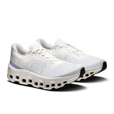On Cloudmonster 2 women's road running shoes in ivory and Nimbus color, featuring a sleek athletic design and breathable mesh upper.