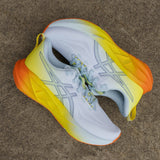 Men's ASICS Novablast 5 neutral daily running trainers in vibrant Sunny Sizzle color, featuring breathable mesh and cushioned sole.