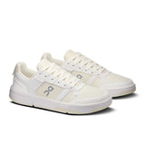 On THE ROGER Clubhouse men's tennis shoes in white with blue accents, featuring breathable mesh and cushioned sole for tennis play.