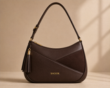 Brown Bagsor curved shoulder bag with tassel detail, featuring a stylish design and adjustable strap for everyday use.