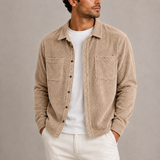 Men’s Zexov corduroy overshirt jacket with long sleeves and button-up front, displayed hanging on a wooden hanger.