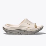 Hoka Ora Recovery Slide 3 shoes in Alabaster and Stardust with cushioned straps and a molded footbed for comfort.
