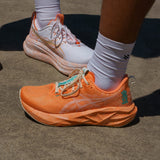 Unisex ASICS Novablast 5 Tokyo neutral daily trainers in sun peach color with breathable mesh upper and cushioned sole.